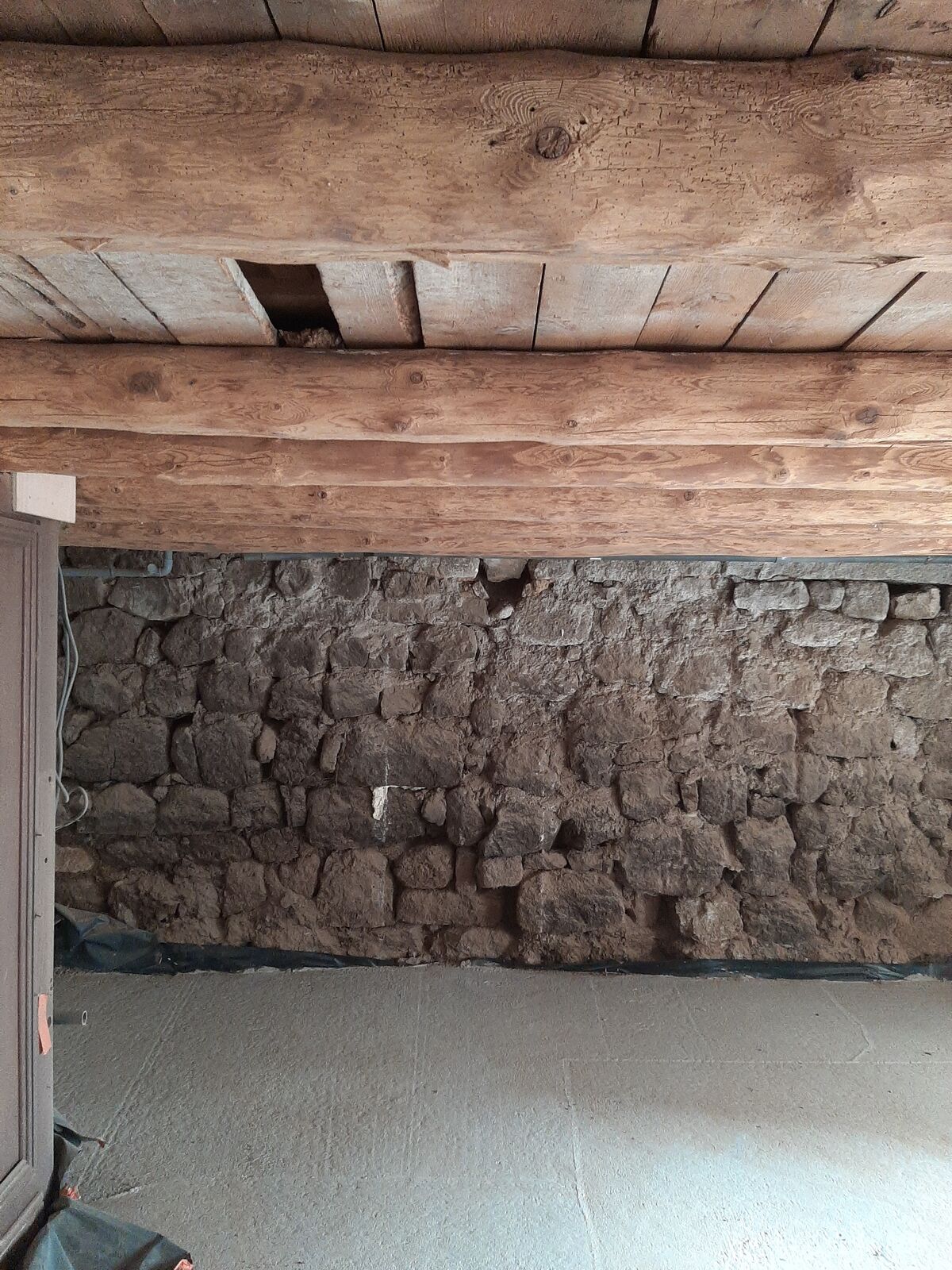 Le même mur en pierre et ses poutres en bois après sablage, pierre et bois éclaircis