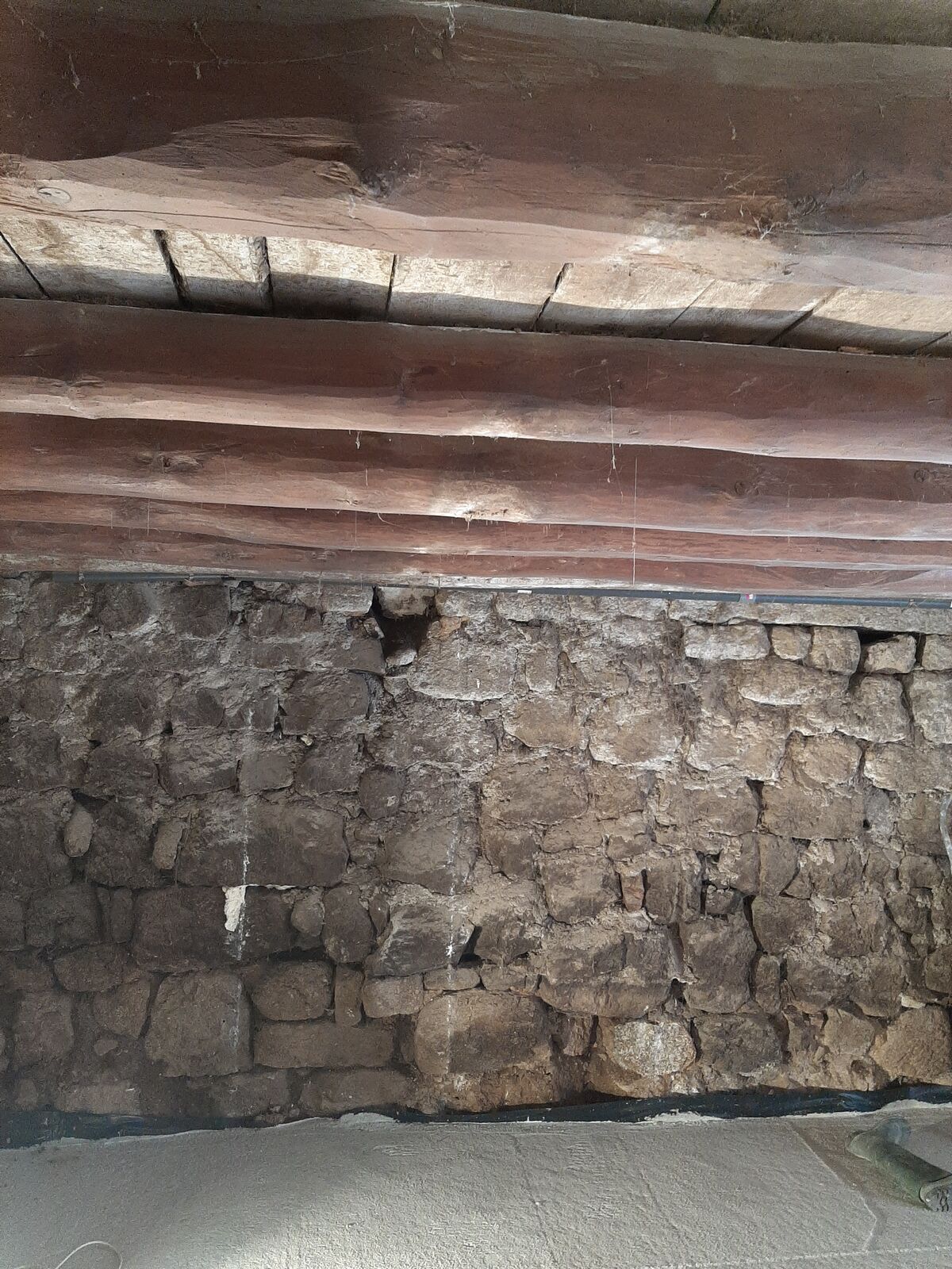 Mur en pierre et poutres en bois encrassés avant sablage